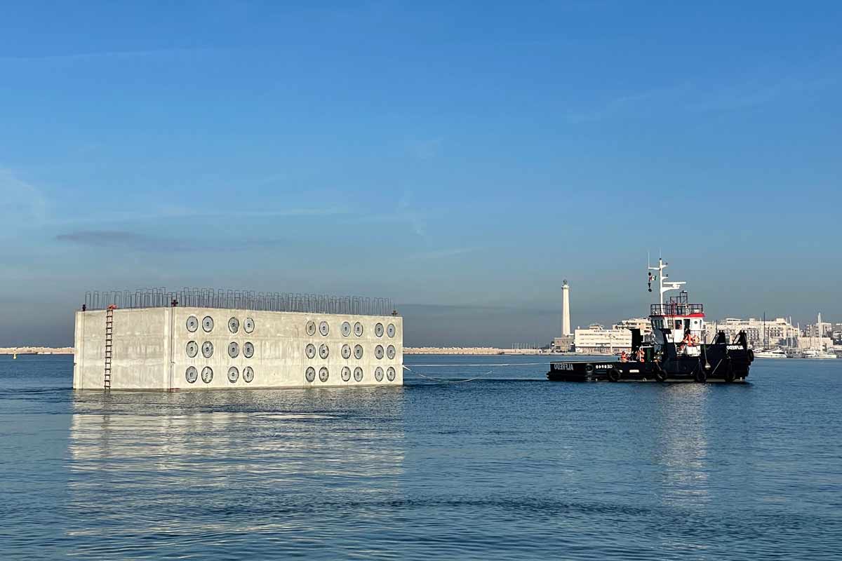 Cassone cellulare in calcestruzzo armato in galleggiamento, trainato da un rimorchiatore nel porto di Bari